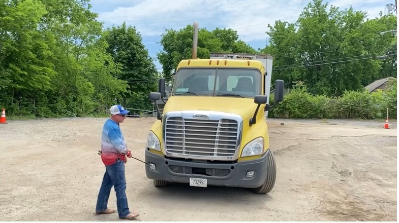 Front of semi truck with instructor pointing to it