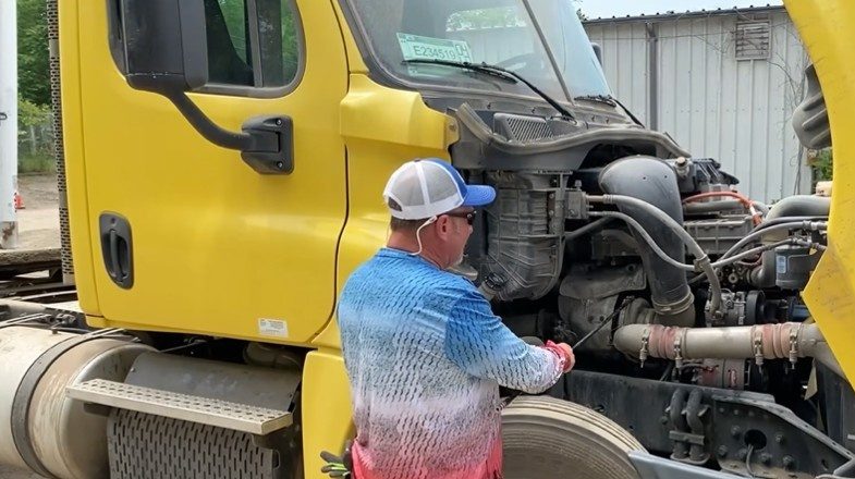 Passenger side engine compartment system of a semi truck. Instructor pointing