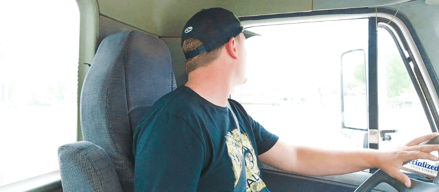 Student driving a semi truck, looking out driver side window