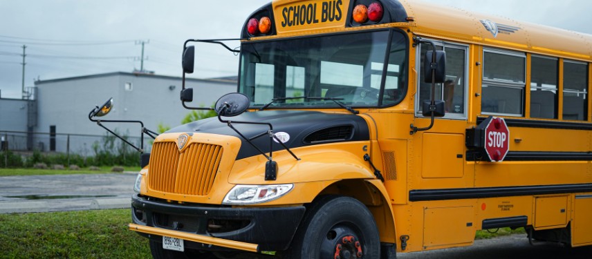 A yellow school bus with its stop sign extended, parked outdoors